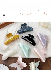 Gros plan de pinces à cheveux élégantes aux couleurs marbrées sur fond de soie blanche
