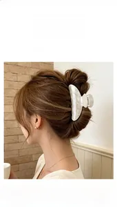 Gros plan d'une pince à cheveux blanc nacré en acétate avec strass sur un chignon