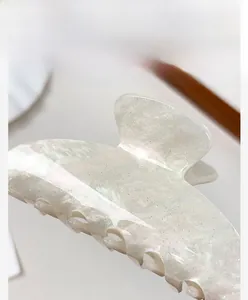 Gros plan d'une grande pince à cheveux blanc crème avec finition nacrée scintillante
