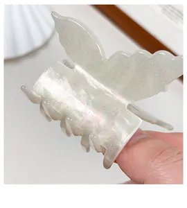 Détail macro d'une pince à cheveux papillon nacrée avec finition en résine et poudre dorée