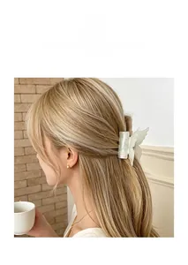 Pince à cheveux papillon nacrée en acétate sur des cheveux blonds ondulés