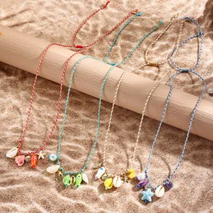 Détail de quatre pendentifs marins faits main avec coquillages et étoiles de mer sur sable