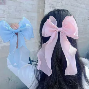 Close-up of pink and blue organza bow hair clips with long ribbons on a model
