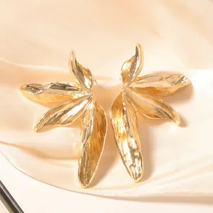 Chic vintage golden leaf earrings with detailed texture on elegant silk background