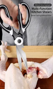 Strong stainless steel kitchen shears cutting raw chicken on a wooden board