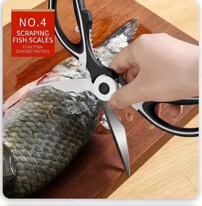 Detail showing multifunctional stainless steel scissors scraping fish scales on a wooden board