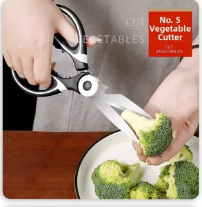 Close-up of stainless steel kitchen shears cutting fresh broccoli florets