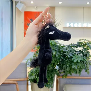 Detail of a black plush pony keychain with golden metal ring and soft fuzzy texture