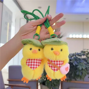 Detail of yellow plush duck charms with green hats and scarves held by hand