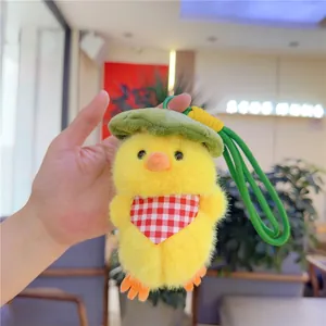 Close-up of plush yellow chick keychain featuring a green leaf hat and red plaid scarf