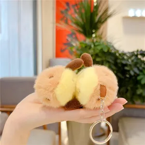 Close-up of cute plush sweet potato keychain held in hand showing soft texture