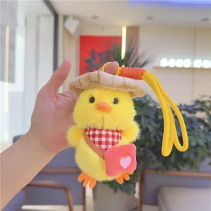 Detail of cute yellow plush duck keychain with a straw hat and red heart crossbody bag
