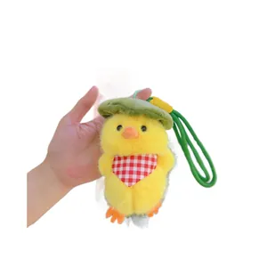 Plush yellow duck keychain with green leaf hat and checkered scarf on a white background