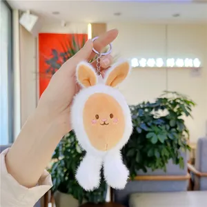 Close-up of a plush white bunny keychain being held, featuring soft fabric and metal ring