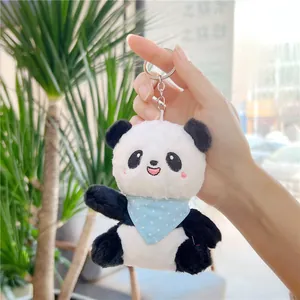 Detail of plush panda keychain with blue polka dot bib held by hand in natural light