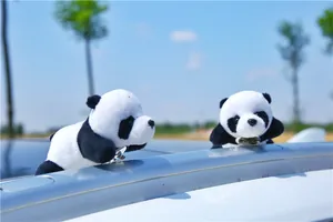 Detail of plush panda clips attached to a car roof rail against a clear blue sky