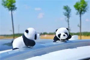 Detailed view of plush panda figures mounted on a car roof rack with outdoor background