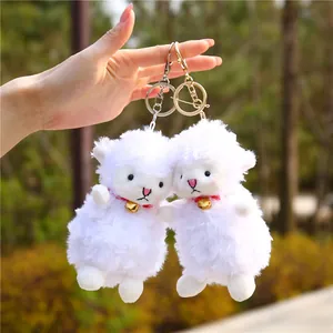 Close-up of white plush lamb keychains with golden bells and soft fleece texture
