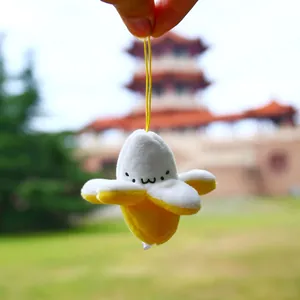 Close-up of a cute plush banana keychain with a smiling cartoon face and yellow strap