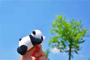 Close-up of a plush panda keychain with soft fur and metal ring held against a blue sky
