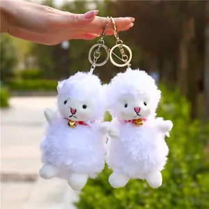 Close-up of white plush lamb keychains with golden bells and soft fluffy texture