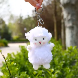 Cute white fluffy sheep plush keychain with silver lobster clasp on a nature background