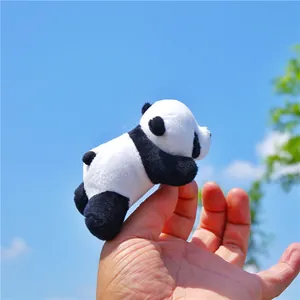 Mini plush panda brooch toy held against a blue sky background showing soft texture