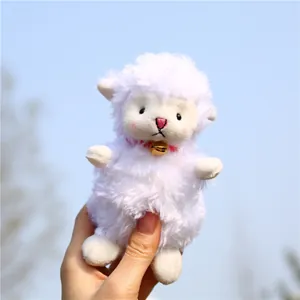 Close-up of white plush sheep keychain with a red collar and a golden metal bell
