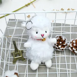 Close-up of white plush sheep pendant with red ribbon and gold bell in a cozy basket
