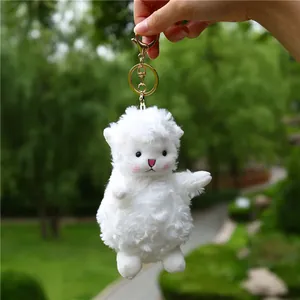 Close-up of white plush lamb keychain with golden clasp and soft fluffy texture