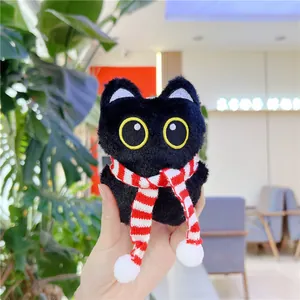 Detail shot of a plush black cat pendant with a red and white striped scarf