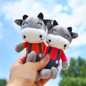 Close-up of cute plush cow keychain charms with striped shirts and blue overalls