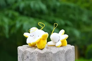 Detailed view of three cute banana plush charms with embroidered faces on stone base