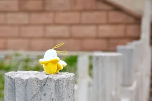 Macro detail of peelable banana plush pendant with yellow strap on stone pillar