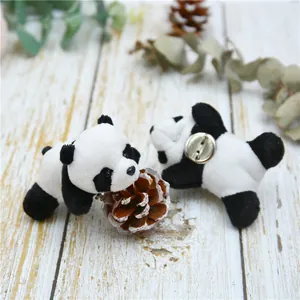 Detail view of the soft plush panda brooch with its secure metal pin on a wooden surface