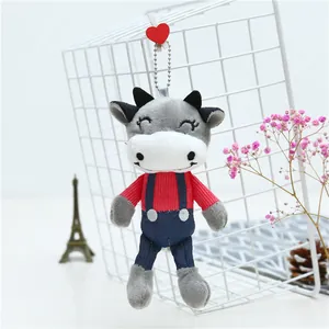 Detail of cartoon plush cow keychain with red striped shirt and wooden heart clip