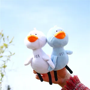 Lot de porte-clés canards en peluche blanc et bleu avec long cou devant un ciel bleu extérieur