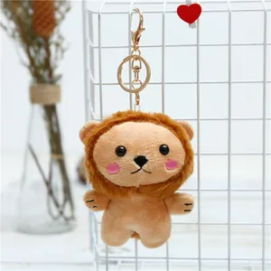 Cute plush lion keychain with brown mane and golden metal clip on white grid background