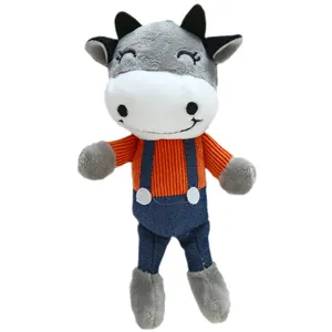 Cute gray and white stuffed cow doll in orange striped sweater and blue overalls