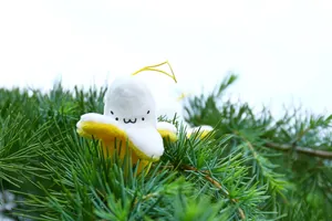 Detail of banana plush keychain with cute expression hanging on pine branch