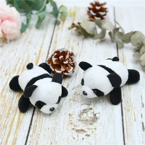 Detailed view of two cute panda plush charms on a warm wooden surface with decor
