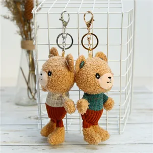 Detail of two cute teddy bear plush keychains with metal rings hanging on a white grid