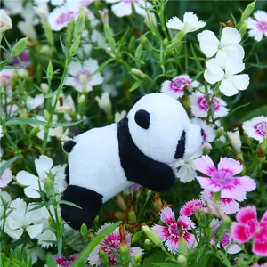 Close-up of a plush panda brooch in prone position nestled among pink dianthus flowers