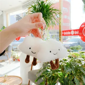 Close-up of white plush cloud keychain with embroidered smile and metal lobster clasp