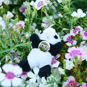 Detail of cute plush panda brooch with metal safety pin fastener on a floral background