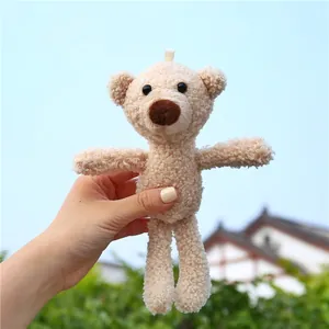 Détail d'un petit ours en peluche marron clair avec texture bouclée pour sac ou porte-clés
