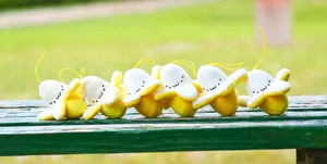 Close-up of cute peeled banana plush charms with funny faces on a green wooden bench