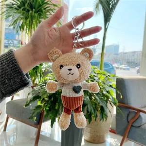 Detail of cute teddy bear keychain with white checkered shirt and orange corduroy shorts