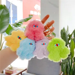 Handheld display of five colorful plush monster keychains with soft fur and gold rings