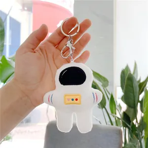 Plush astronaut keychain with embroidery details being held to show compact size